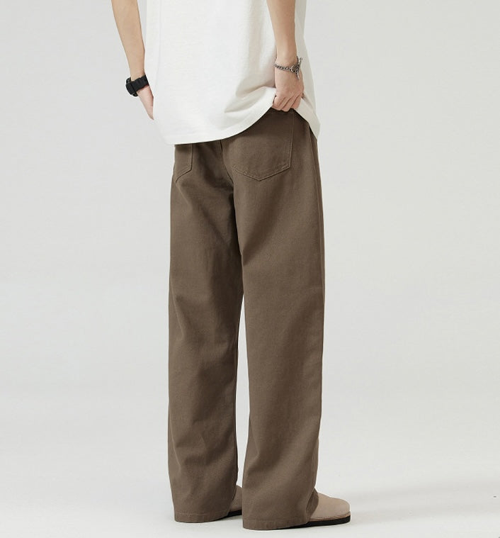 Person wearing brown Japanese Chino Pants and a white shirt on a plain background