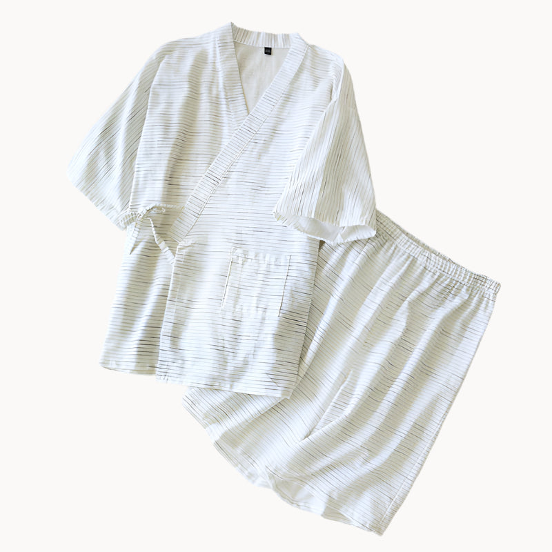 White striped pajama set on a bed with a wooden nightstand.