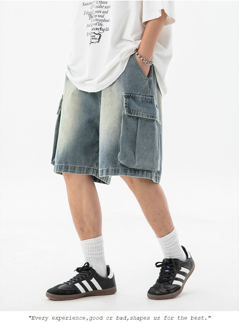 Person wearing a white oversized shirt, denim cargo shorts, and black Adidas sneakers on a white background.