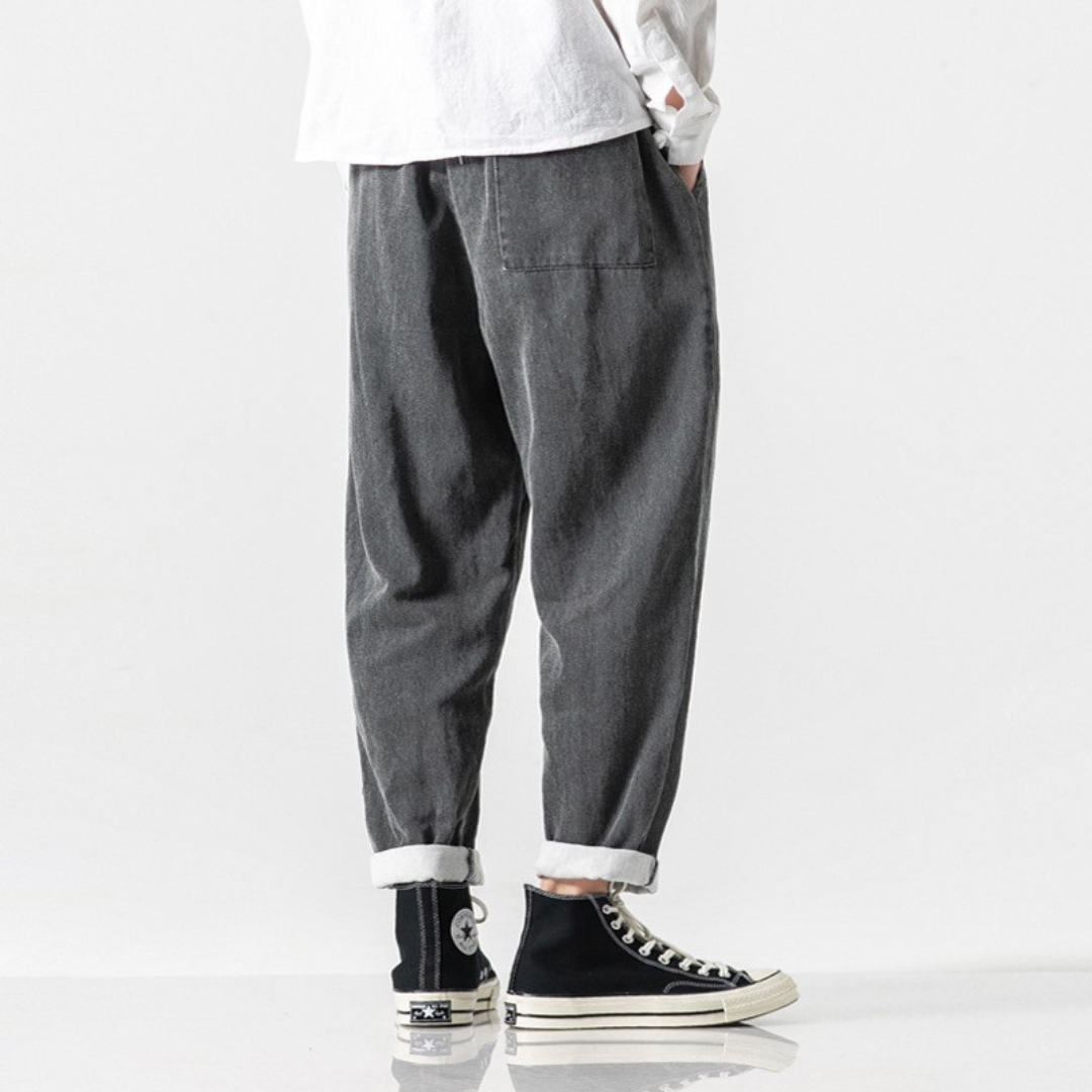 Person wearing gray pokku pants and black sneakers on a white background